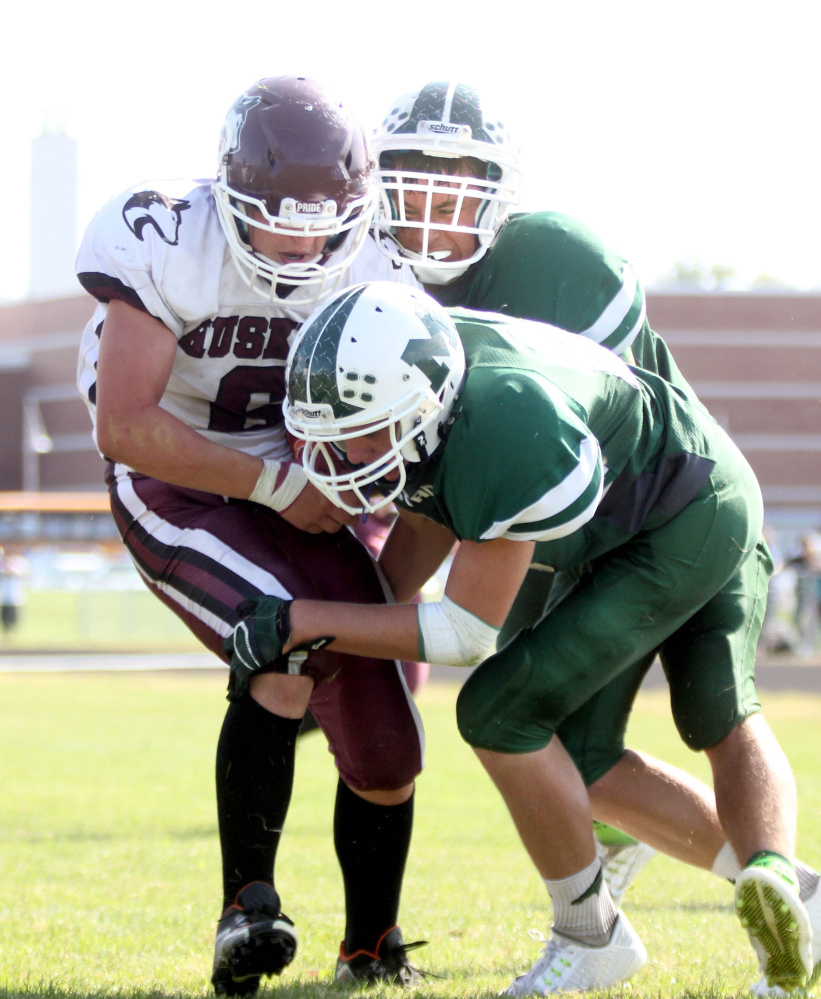 Photo by Jeff Pouland 
 Mount View High School's Ethan Sewell-Berry (top) helps teammate Gavin Simpson tackle Maine Central Institute's Adam Bertrand near the goal line during a Little Ten Conference game earlier this season in Thorndike.