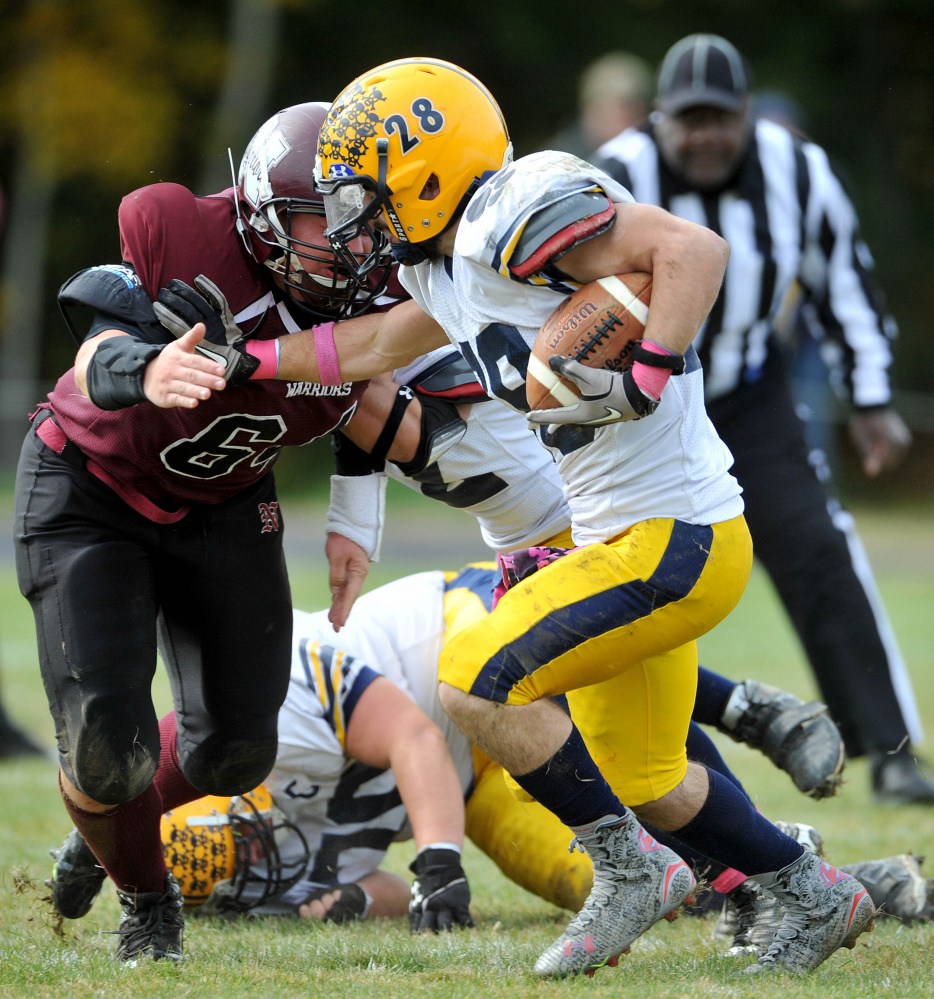 Mt. Blue High School’s Christian Whitney (28) stiff-arms Nokomis High School’s Jake SeeHusen (64) on Saturday in Newport.