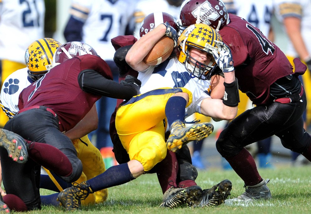 Mt. Blue High School’s Nate Pratt-Whitney (14) gets smothered by a group of Nokomis High School defenders Saturday in Newport.