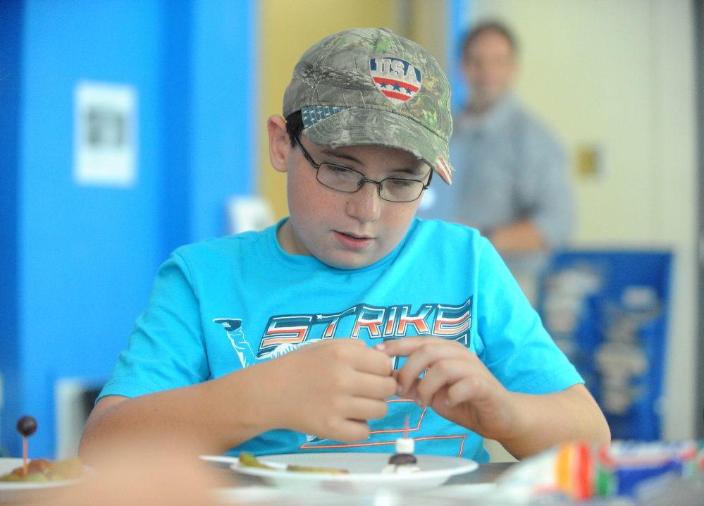 Bryce Jewell, 10, creates edible art using apples, grapes, marshmallows, caramel and toothpicks during art class at Cornville Charter School in Cornville on Wednesday. Every Wednesday for two hours students at the Cornville Regional Charter School get hands-on instruction from two artists and two musicians who visit students in groups.