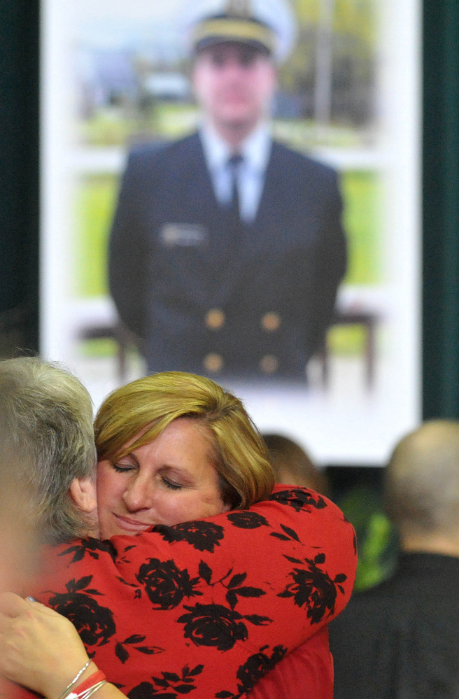 Deborah Roberts Holland, mother of Michael Holland, is comforted by a friend during a celebration of her son at the Jay Community Building on Wednesday.