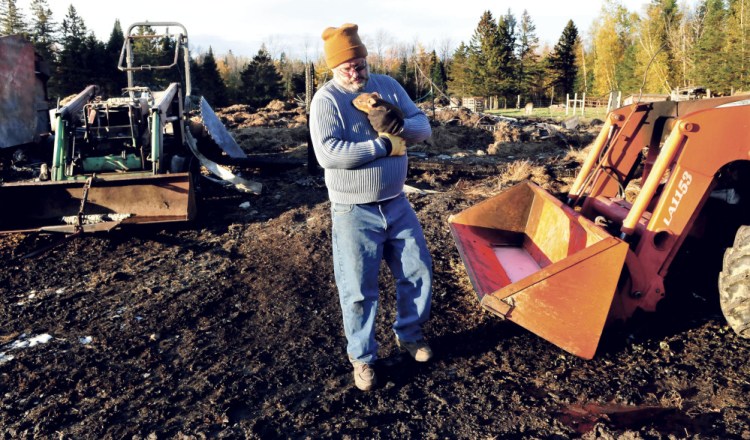 Walking between two burned tractors and the flattened remains of a large barn destroyed by fire early Monday, homeowner Jeff Chadbourne carries a three-day-old piglet he named Miracle. Several goats, pigs and chickens died in the fire. Miracle was the only piglet that made it out safely.