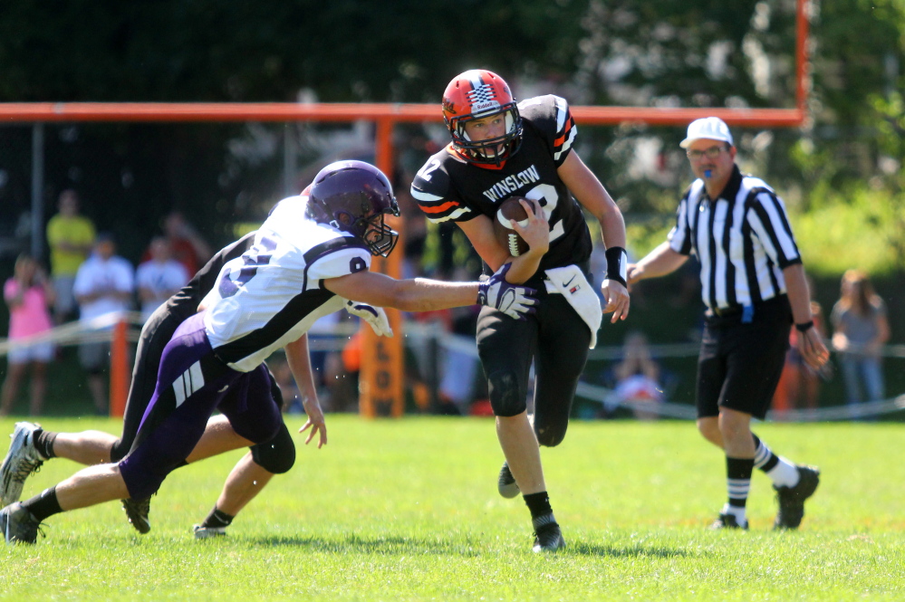 Photo by Jeff Pouland 
 Winslow High School quarterback Jacob Trask, right, tries to break free from John Bapst defender Spencer Baron during the first half of a game at Poulin Field in Winslow earlier this season.