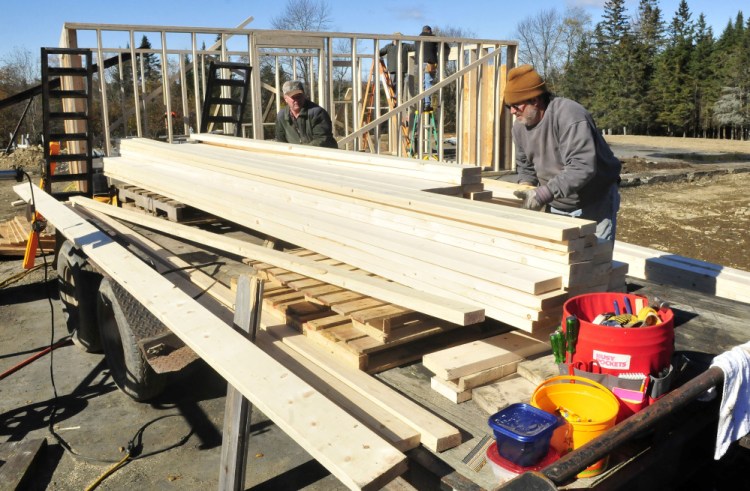 Homeowner Jeff Chadbourne, right, and friend Rick Clowry and other volunteers help build a new barn at the farm in Harmony on Monday.