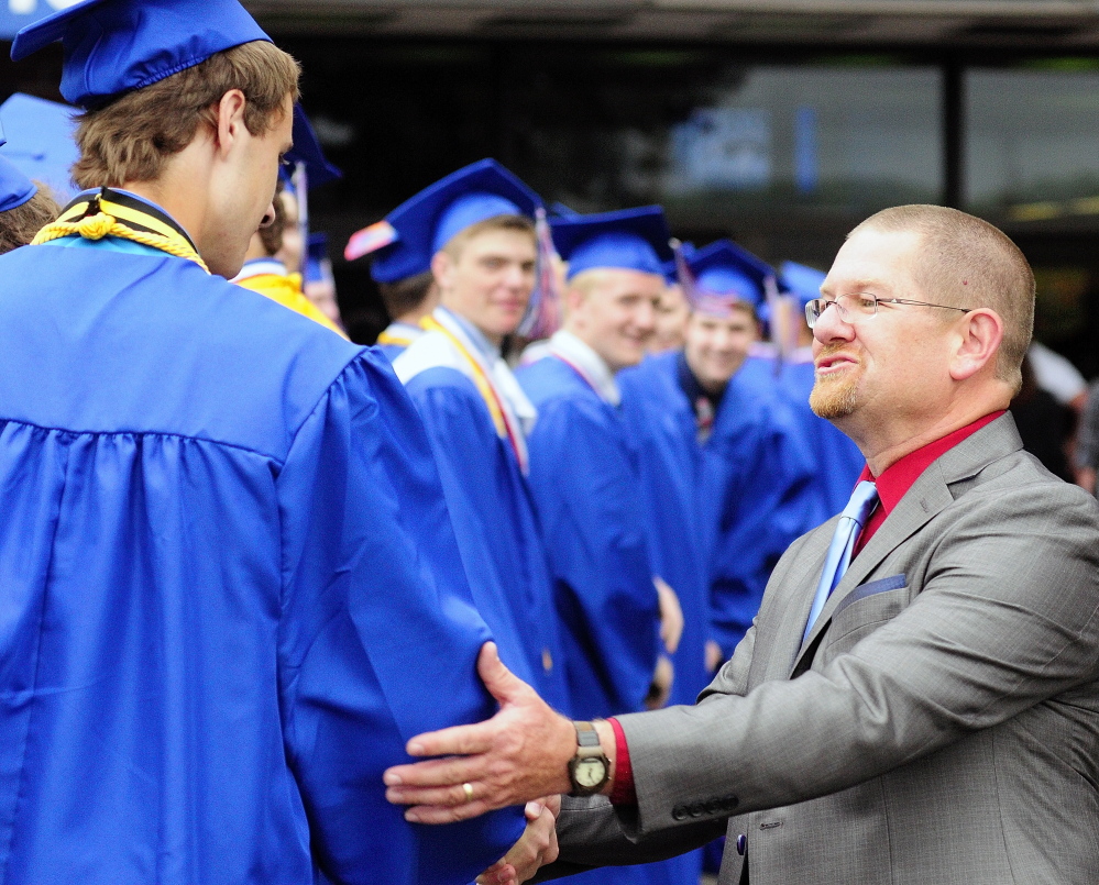 Oakland Police Officer Tracey Frost, who is the school resource officer at Messalonskee High School, shakes hands with students before graduation in June 2014 at the Augusta Civic Center. Frost works with school officials to handle problem students, Oakland Police Capt. Rick Stubbert said.