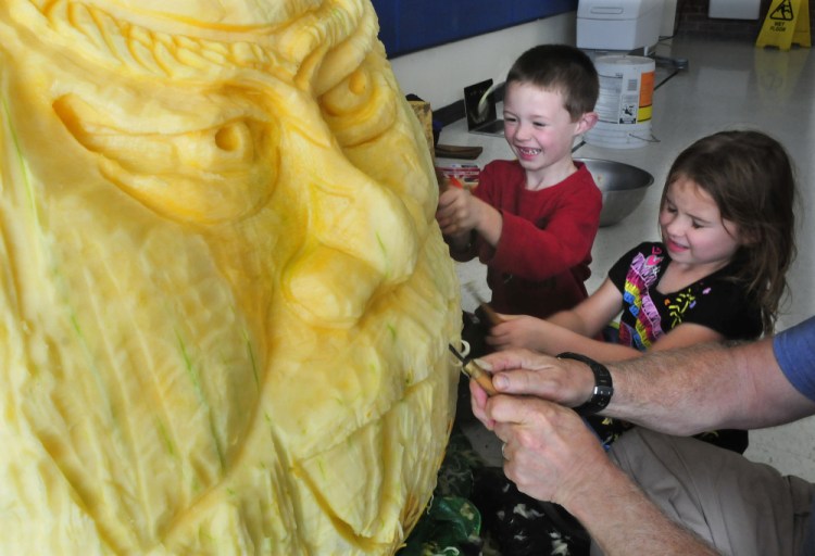 North Street Elementary School students Gauge McIntyre and Ana Lucia Cardenas carve around the face of a giant pumpkin at the Skowhegan school on Thursday.