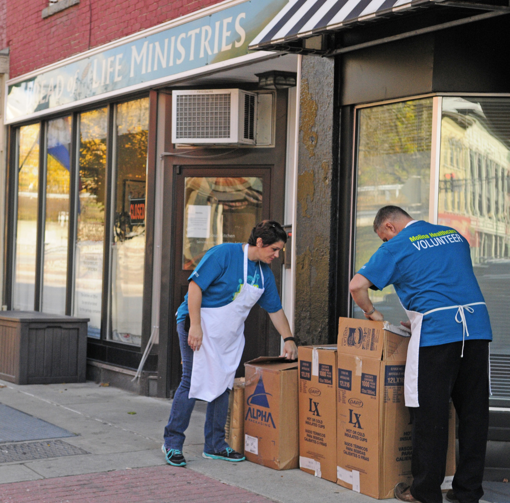 Tina Dubois, left, and Kris Pahel, volunteers from Molina Healthcare, set up boxes to give away hats, gloves and socks on Friday at Bread of Life Soup Kitchen in Augusta.