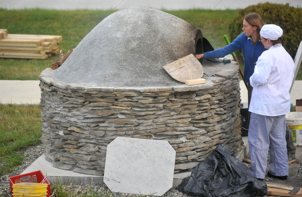 Katherine Creswell, farm manager at Kennebec Valley Community College helps culinary student, Brenda Madden with the wood oven during class at the Alfond campus on Friday.