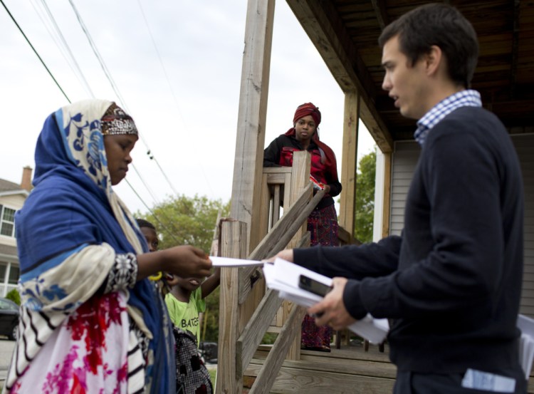 Democrat Ben Chin, a candidate for Lewiston mayor, hands out campaign information Tuesday. Chin is being attacked online by the Maine Republican Party.