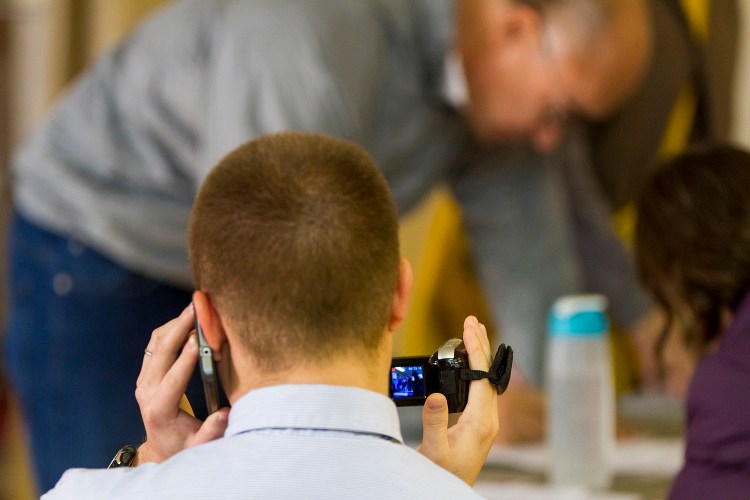 Shane Belanger, a volunteer with a group called Project Dirigo, videotapes Will Ritch as he signs a petition calling for background checks on gun purchasers Tuesday. Ben McCanna/Staff Photographer