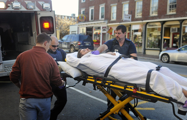 Medics wheel a man with stab wounds into an ambulance on Water Street in Hallowell on Monday after he collapsed in the entrance of Dom’s Barber Shop.