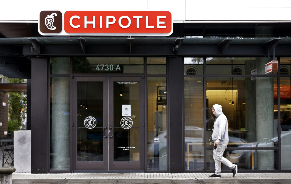 A pedestrian walks past a closed Chipotle restaurant Monday in Seattle.