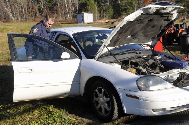 Maine State Trooper Seth Allen on Wednesday secures a car seized at a Monmouth used car lot that allegedly was used as a get away car in a robbery at the Randolph IGA on Saturday.