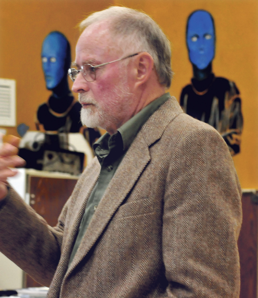 Speaking between images of the Blue Men musicians, John Foss of Palermo speaks to Madison Area Memorial High School students about his career playing trumpet during Career Day on Wednesday.