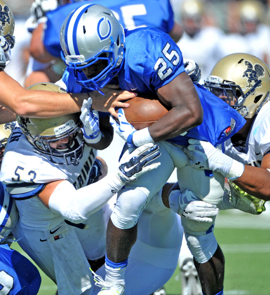 Colby’s Jabari Hurdle-Price (25) is tackled by Trinity’s Dago Picon-Roura, right, and Kevin Martin (53) during a game earlier this season. The Mules host Tufts on Saturday in their final home game of the season.