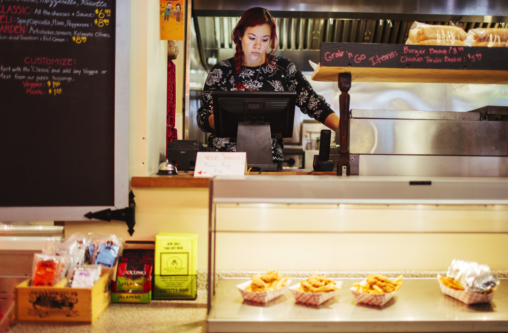 PORTLAND, ME - NOVEMBER 4: Hilltop Superette employee Ambre Davidson works the register in Portland, ME on Wednesday, November 4, 2015. Davidson would be affected by a state-wide increase to a $12/hour minimum wage. "I have a four year old, and a couple dollars extra an hour would be a huge thing for me, especially with child care," Davidson said. Davidson, who works two jobs, said she was recently notified of a rent increase for her apartment next year, and a jump in the minimum wage would make her better able to sustainably live in Portland. (Photo by Whitney Hayward/Staff Photographer)