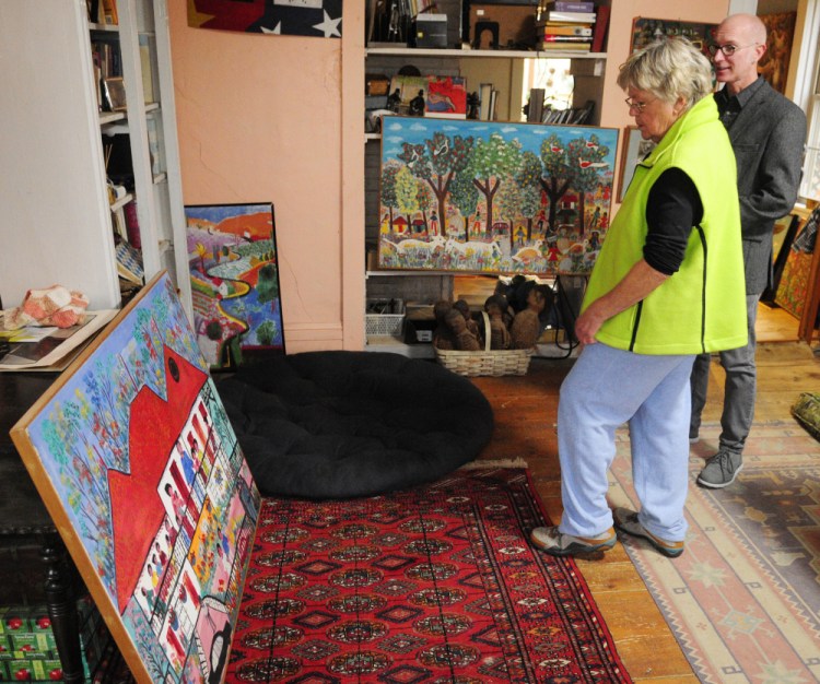 Barbara Skapa, left, and Kent Shankle, executive director of the Waterloo Center For The Arts, look at Haitian paintings on Friday at Skapa’s Mount Vernon home. Skapa collected several paintings by Gerard Fortune when she worked in Haiti.