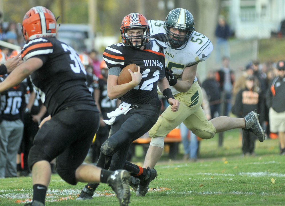 Winslow quarterback Jacob Trask (12) is tackled from behind by Mt. Desert Island linebacker Dan McGregor (55)during a Big Ten Conference semifinal Saturday in Winslow.