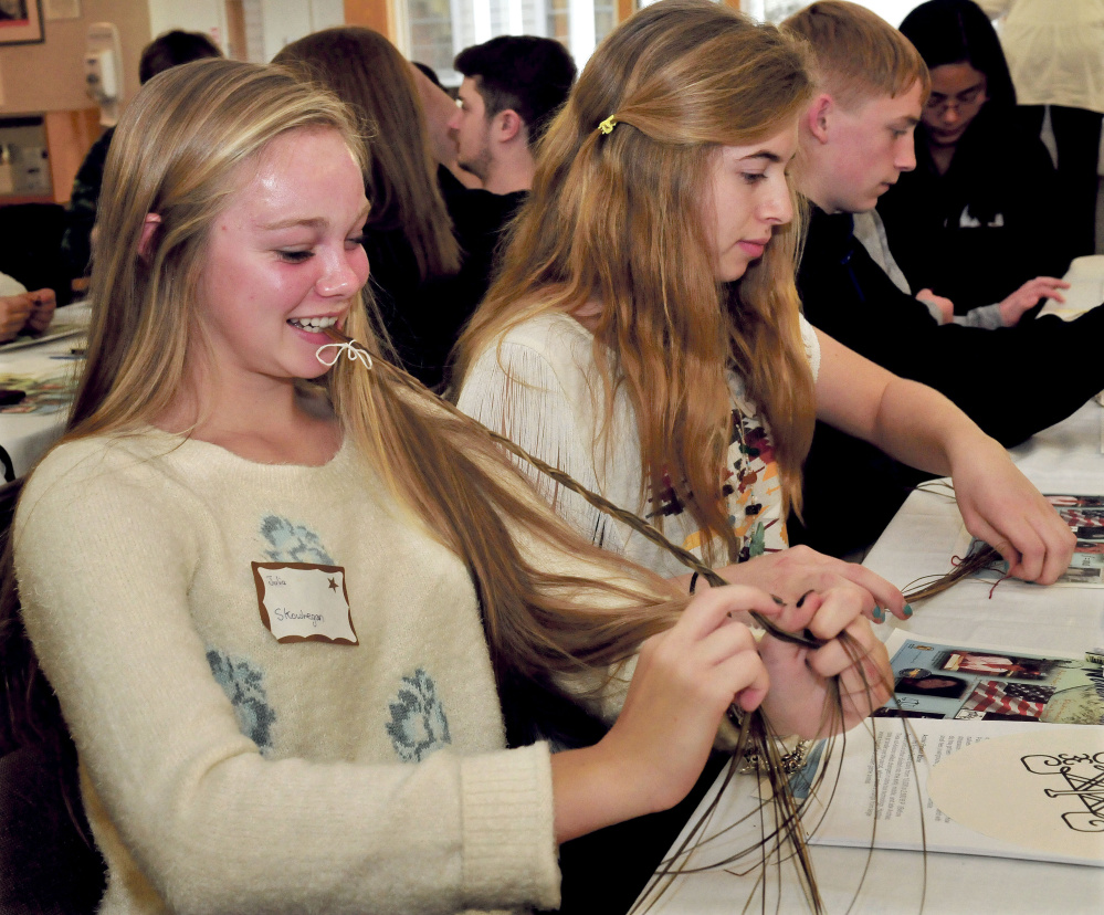 Skowhegan Area High School students Julia Steeves, left, and Anessa McGann and students from Carrabec and Upper Kennebec Valley high schools try their hands at making prayer braids taught by Pam Outdusis Cunningham of the Penobscot tribe during a forum on Maine’s Wabanaki tribes and cultures Thursday at the Margaret Chase in Skowhegan