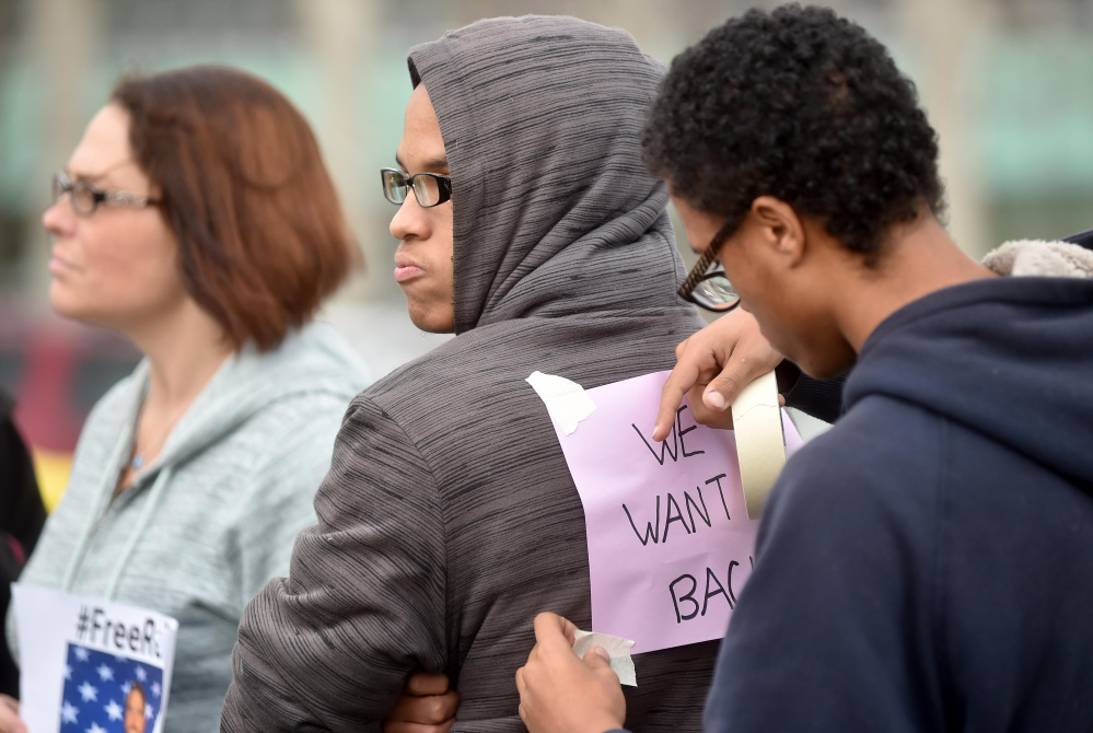 Jerry Shamble, 18, tapes a sign in support of Waterville Senior High School Principal Don Reiter to his twin brother Terry’s back at a rally at Waterville Senior High School Friday. Reiter, accused of propositioning a student, has been on administrative leave since Sept. 1.