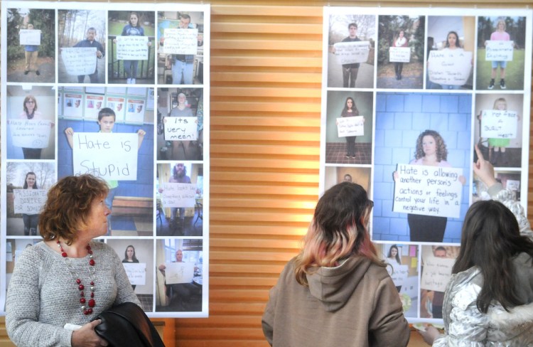 People examine posters Wednesday as part of  “The Sign Project” during a reception for the art show at the University of Maine at Augusta. The exhibition, which explores the meaning of hate, is part of a course offered by UMA through a dual enrollment program, which allows Cony High students to earn high school and UMA college credit at the same time.