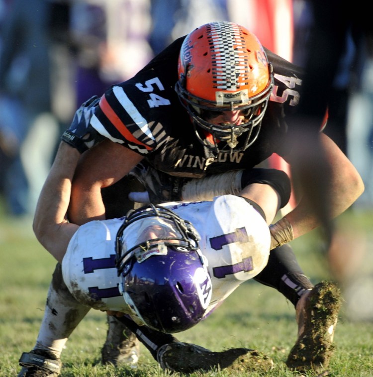 Winslow High School’s Alec Clark, top, hits Waterville’s Daniel Jolin during the 2014 conference title game.