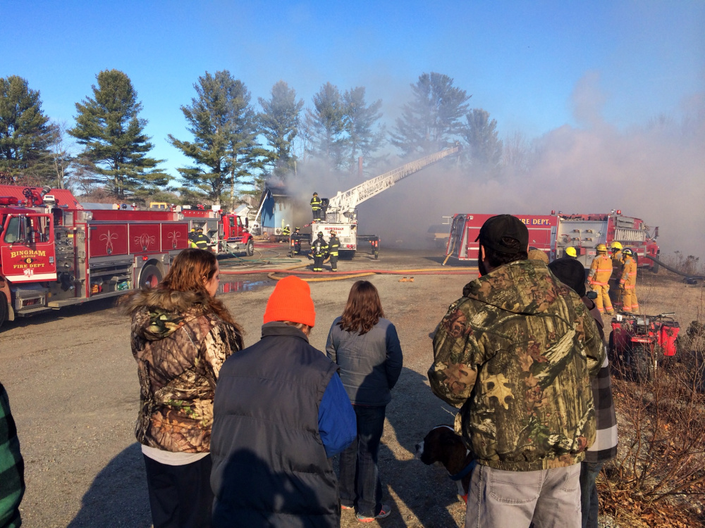 Alicia Lumbert, left, and her mother, Carolyne Surma, second from left, watch with friends and family as Surma’s house was destroyed by fire Tuesday morning. Surma said she was in the kitchen baking a pie for Thanksgiving when the fire started upstairs. The family built the home after another one burned down in 1994.