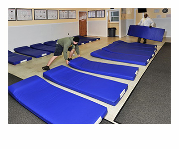 Brian Marchant, left, and Bonane Rutijanwa, shelter attendants for Portland’s Oxford Street Shelter, set up 16 mats for homeless people to sleep on at the General Assistance Office if needed if the other shelters are filled.