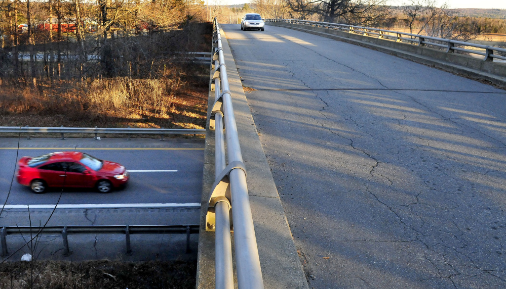 A vehicle travels west on Trafton Road in Waterville on Monday as another passes under the overpass on Interstate 95 where a new interchange will be built.