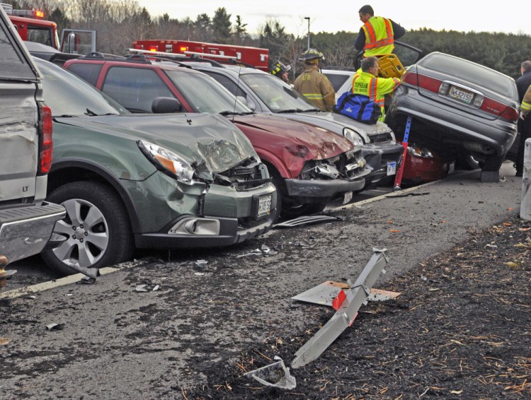 Rescue personnel remove the driver of a gray Buick that collided with seven parked cars on Friday in front of MaineGeneral Medical Center in Augusta.
