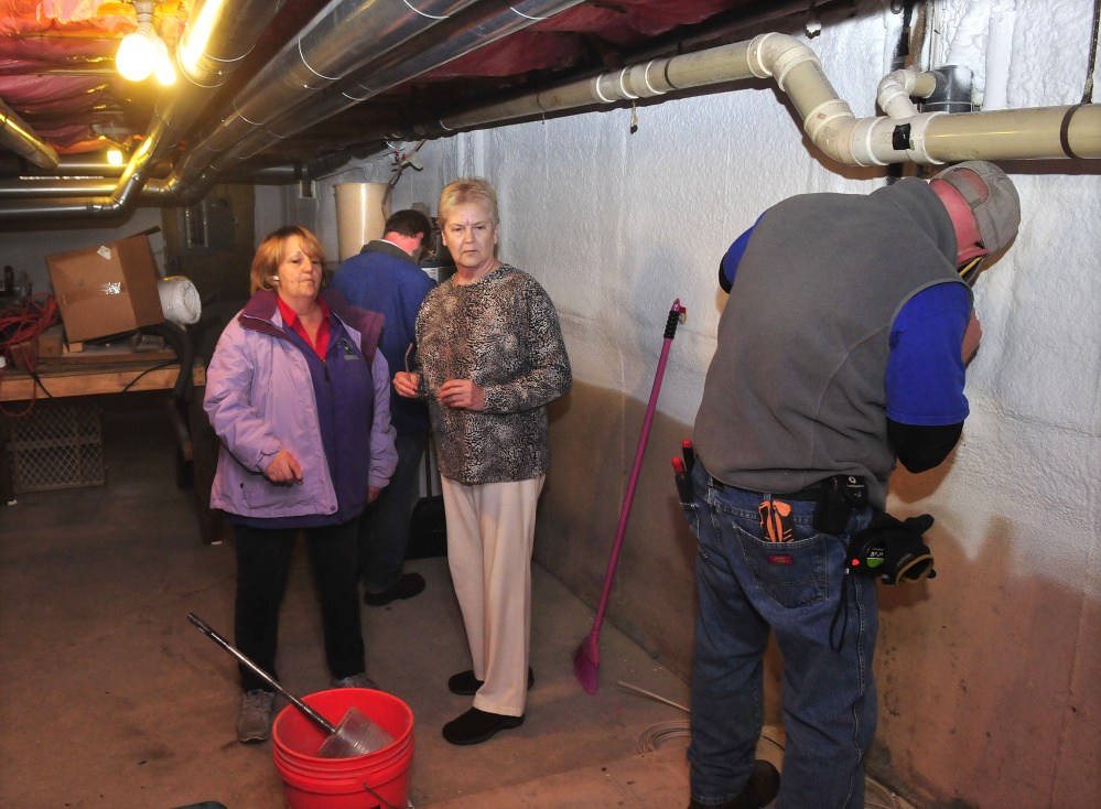 Benton homeowner Dorothy Lavoie, center, speaks with Terry Person Curtis, left, of TP Environmental Consulting as electrician Robert Fago wires controls for a ventilation system to remove radon gases from the basement of Lavoie’s home on Monday. In background is radon specialist Bob Stilwell of Maine Center of Disease Control. The system was donated by the Maine Indoor Air Quality Council as part of its Preventing Lung Cancer One House at a Time program.