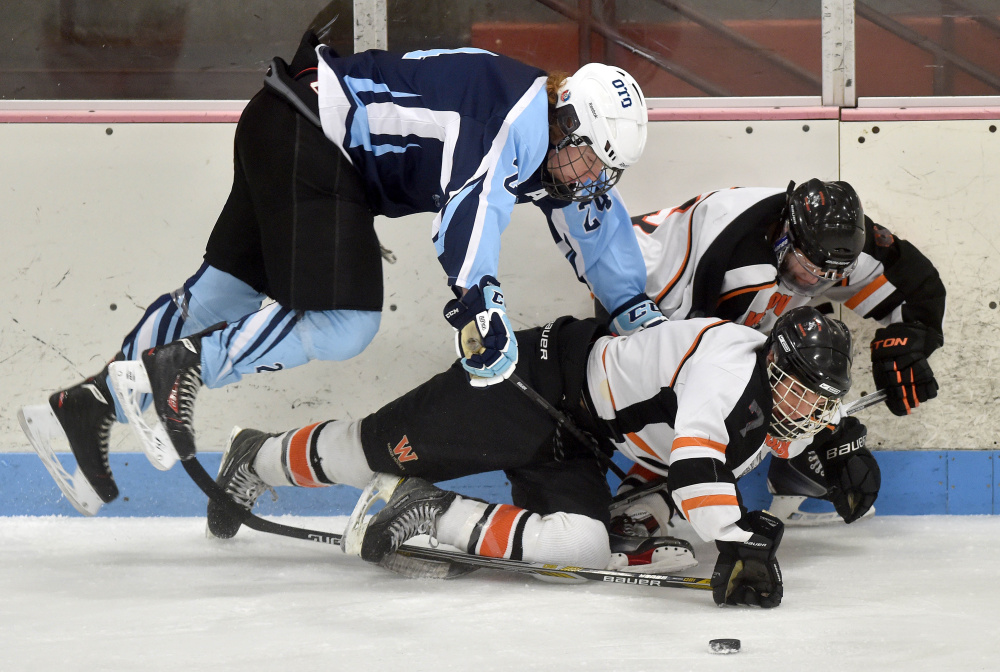 Staff photo by Michael G. Seamans 
 Winslow forward Jimmy Fowler, bottom center, gets knocked over by Old Town/Orono's Chris Hoxie during a Class B North game Saturday night at Sukee Arena.