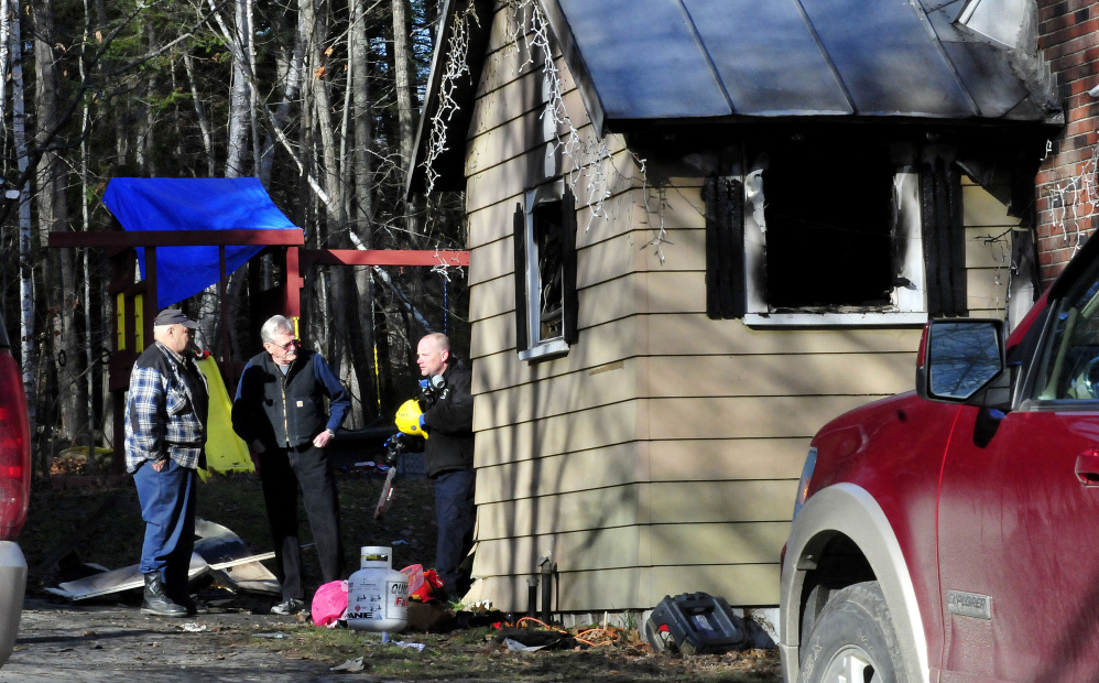Oakland firefighter Vaughn Farnham, left, speaks Sunday with State Fire Marshal’s Office investigator Jeremy Damren at the home of Jon and Betty Belanger, which was seriously damaged by fire Saturday night. Two dogs died in the fire and the family of nine was left homeless.