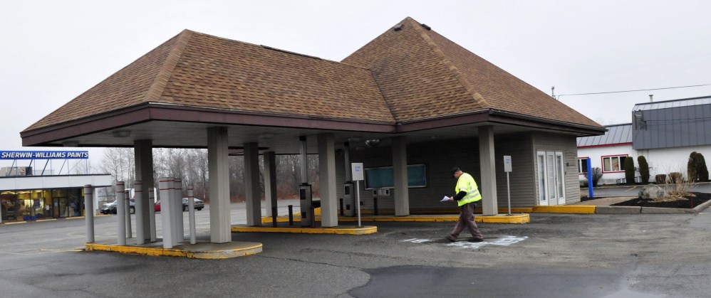 A surveyor works beside a former bank at 345 Main St. in Waterville on Monday. City officials will consider a request to rezone the lot to allow a Taco Bell restaurant at the site.