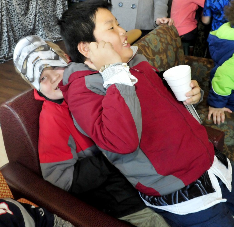 Dressed as a “Star Wars” storm trooper, Jadon Callahan gets squished by Evan Sotiriou during a “Star Wars” movie party at the Waterville Public Library on Sunday.