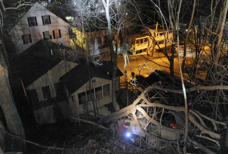 Ready Road Service wrecker operator Bill Maraglia hooks a cable on Friday to a vehicle that was lodged between trees on a banking between Crosby and Laurel streets in Augusta after a police chase. The vehicle’s driver was arrested just before 11 p.m. after a pursuit by Augusta police that ended when he allegedly launched the vehicle over the steep embankment at the dead end of Crosby Street. Two wreckers from Ready Road Service were used to recover the vehicle.