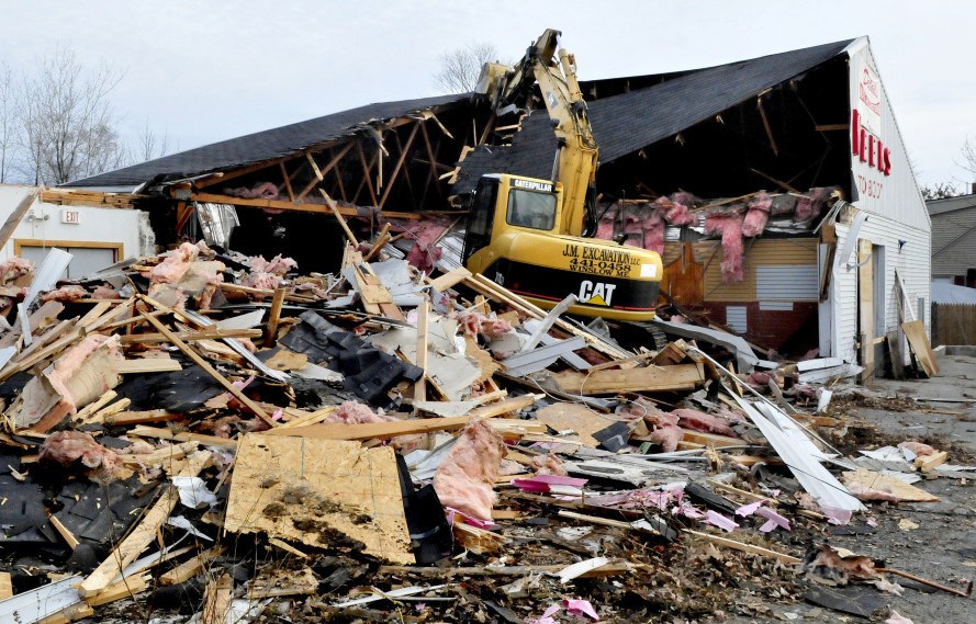 Jeremy Marcoux uses an excavator to demolish the former Weeks Auto Body business on Kennedy Memorial Drive in Waterville on Dec. 21.
