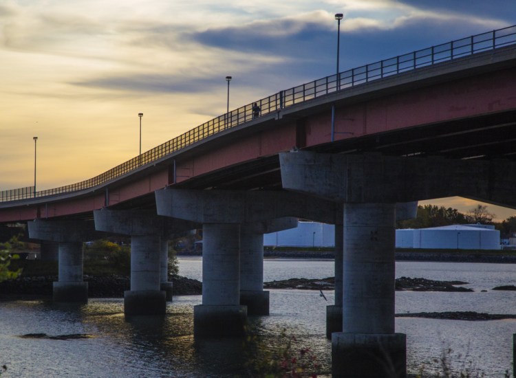 A pedestrian walks across the Casco Bay Bridge in October. A Florida company will operate and maintain the drawbridge starting in early 2016, but the state says users won't notice any difference.