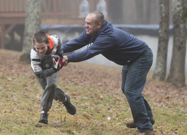 Jamey House plays football with his son Griffin in the back yard of their Lincoln home on Wednesday. The House family sticks close to home and does not engage in many activities that cost money in order to conserve the household budget. “ We do what we can based on what we have” said House. Jamey House lost his mill job in December of 2013 and for a year was a peer support worker for fellow mill employees before taking classes to start a new career in banking. 
