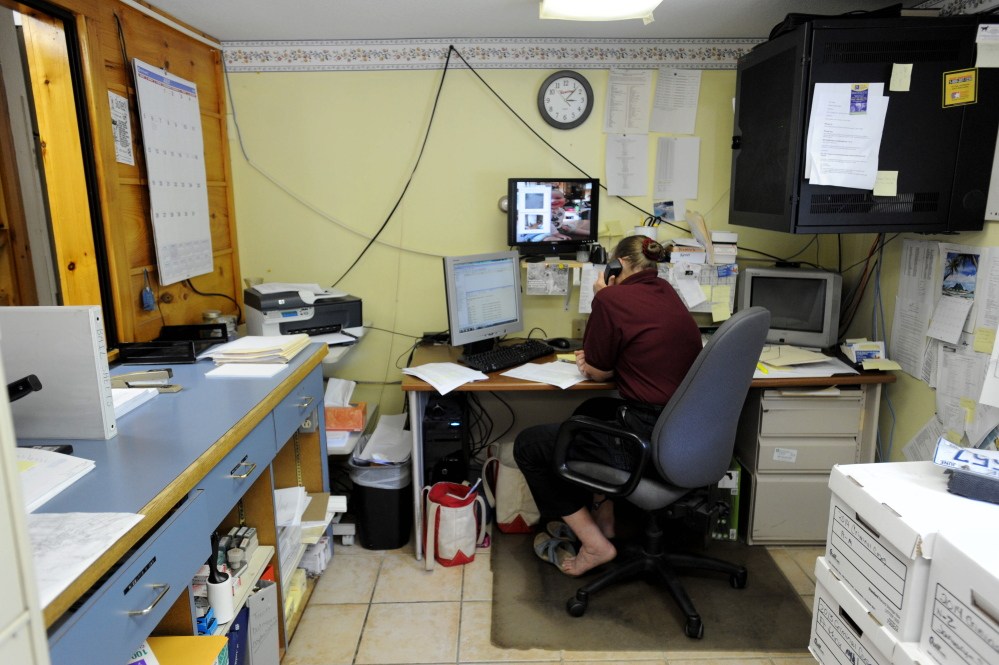 Kathy Gray, dispatcher for the Oakland Police Department, works at her desk in July. The station, in a cramped farmhouse, will be replaced soon by a new building. The town might consider bids on the work next week.