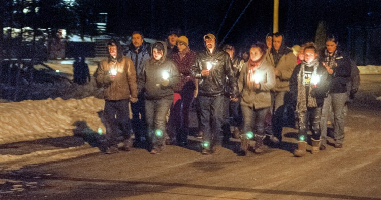A group walks through the Augusta neighborhood where Eric Williams and Bonnie Royer lived during a candlelight vigil Friday in remembrance of them. Williams, 35, and Royer, 26, were shot to death early Christmas morning in Manchester.