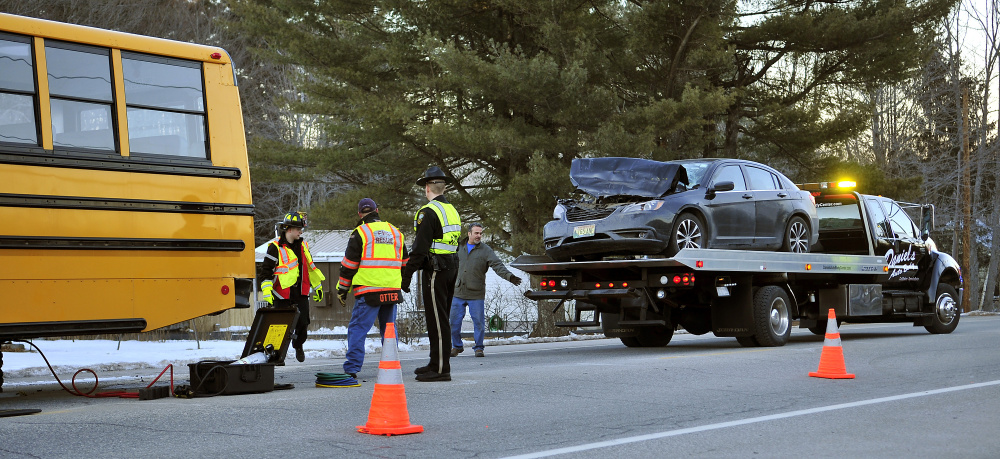 Gardiner firefighters and police officers, along with a tow truck driver, work at the scene of a collision between a car and a school bus on Tuesday on U.S. Route 201 in Gardiner.