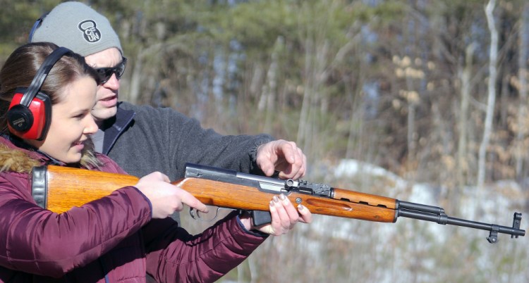 Katherine Pollock fires a rifle under the instruction of Rob Sibley on Wednesday at an Inland Fisheries and Wildlife range in Augusta.