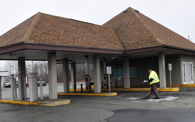 A surveyor works beside a former bank at 345 Main St. in Waterville in December. City officials are considering a request to rezone the lot to allow a Taco Bell restaurant at the site.