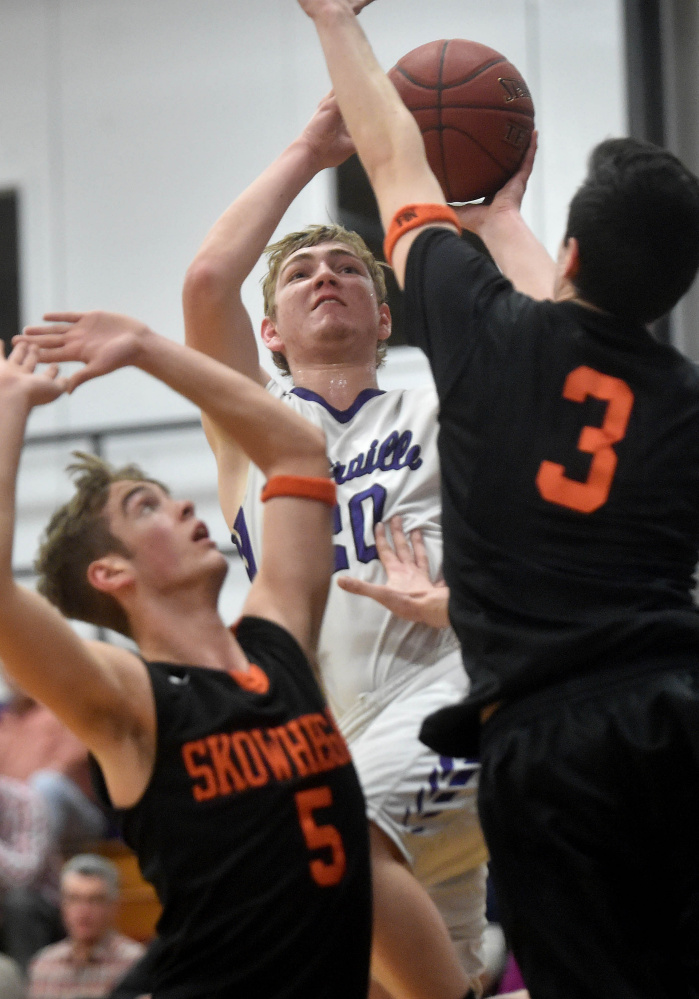 Waterville’s Adam Barre, middle, takes a shot over Skowhegan defenders Issac Witham, left, and Cameron Barnes during a Kennebec Valley Athletic Conference Class A game Tuesday night in Waterville.