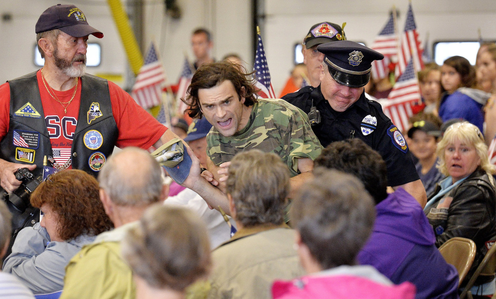 James Roux III of Freeport is escorted out of the 9/11 remembrance ceremony at the Freeport fire department in September. Roux interrupted one of the speakers and started yelling that his father had died on 9/11.