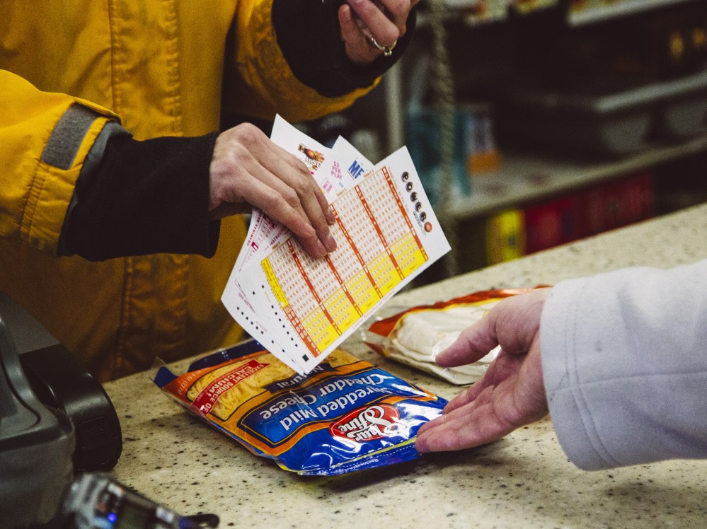 Cashier Sabrina Meserve hands a Powerball ticket to a customer at Paul’s Food Center in Portland on Thursday. Ticket sales soared after no one won the $700 million jackpot on Wednesday. The jackpot reached $800 million Friday, and could top $1 billion if no one wins Saturday, lottery officials say.