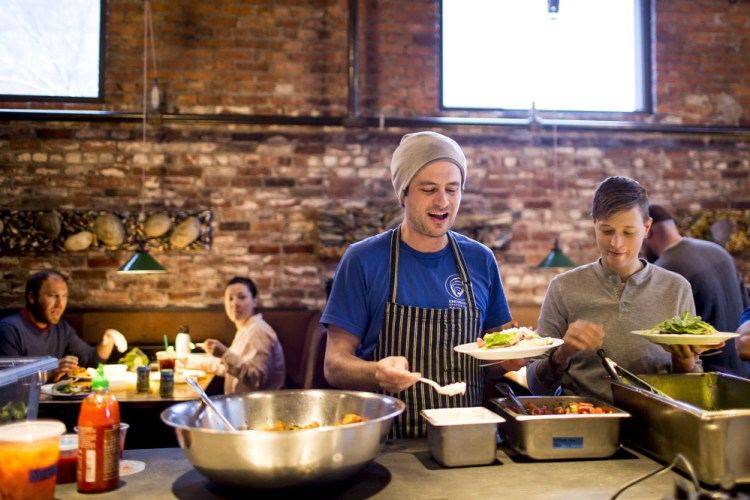 Michael Wiley, center – one of the owners of Hugo’s, Eventide Oyster Co., and The Honey Paw – serves himself the staff meal before the evening shift at Hugo’s.