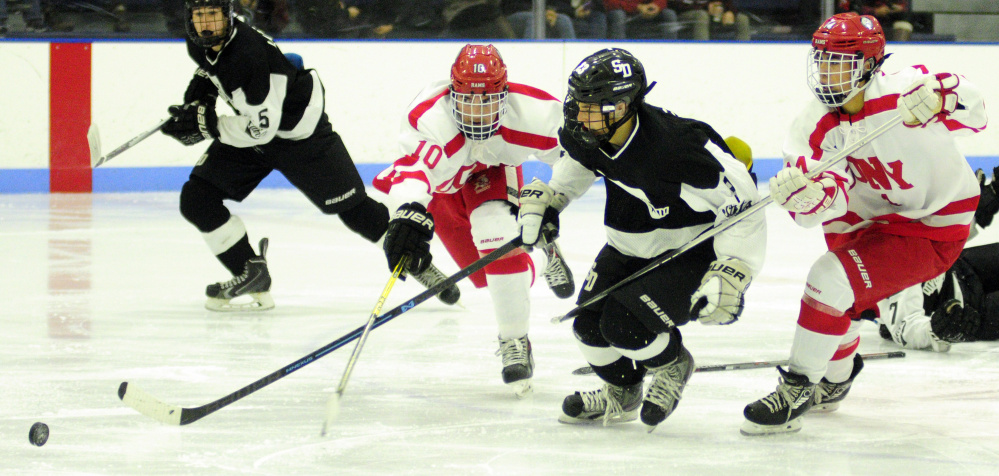 Cony forward Riley Boivin, left, chases a loose puck during a game against St. Dominic earlier this season at the Camden National Bank Ice Vault in Hallowell.