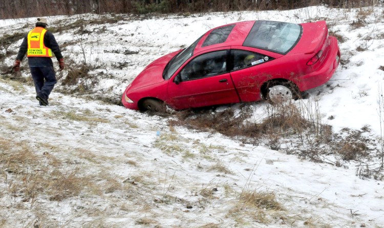 A tow truck operator prepares to pull a car from a ditch in the median strip of I-95 in Waterville as morning snow changed to freezing rain early afternoon.